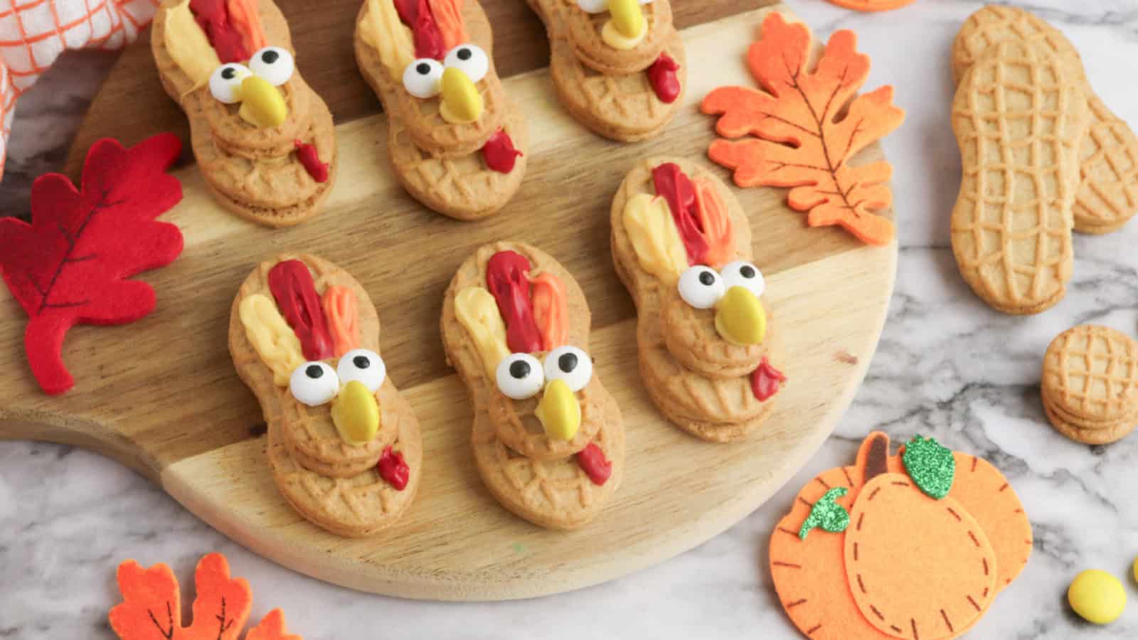 Nutter Butter cookies decorated with candy eyes, yellow candy beaks, and red and orange frosting to look like Thanksgiving turkeys.