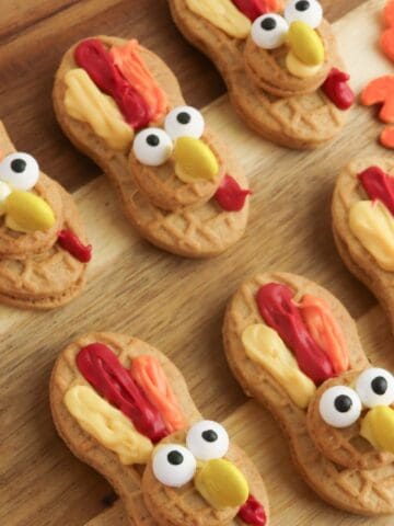 Nutter Butter cookies decorated with candy eyes, yellow candy beaks, and red and orange frosting to look like festive Thanksgiving turkeys.