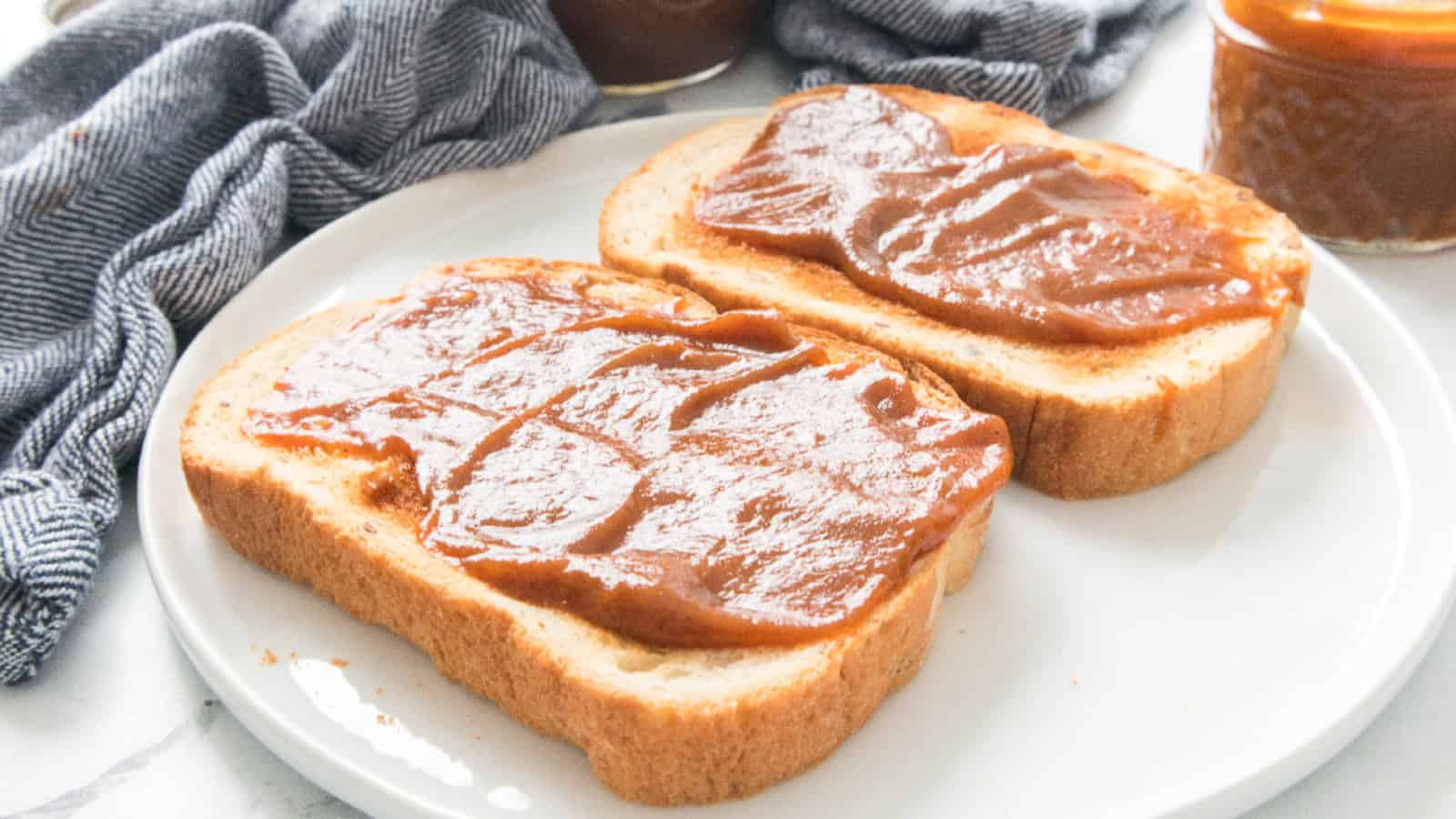 Close-up of toasted bread slices spread with homemade pumpkin butter on a white plate.