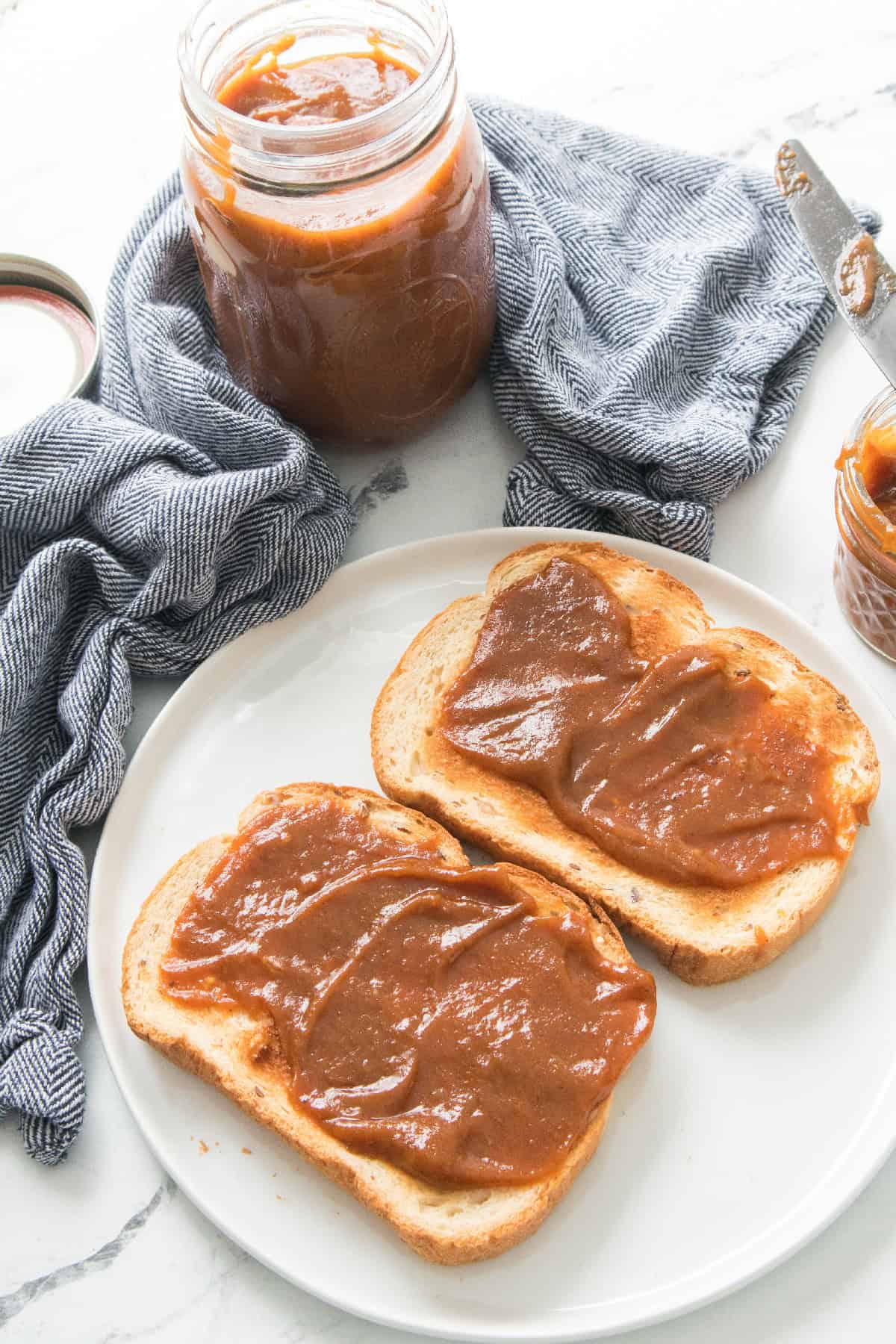 Overhead view of toast topped with pumpkin butter alongside jars.