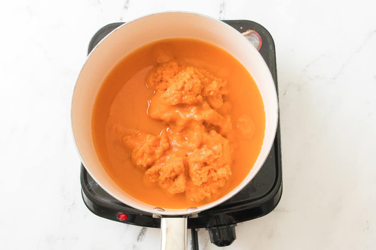 Pumpkin puree and liquid starting to heat and blend in a pot.