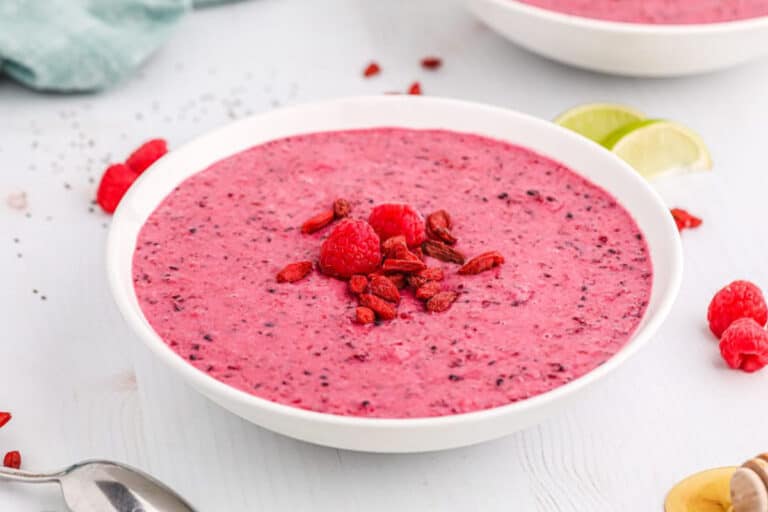 Raspberry smoothie served in a topping-covered bowl.