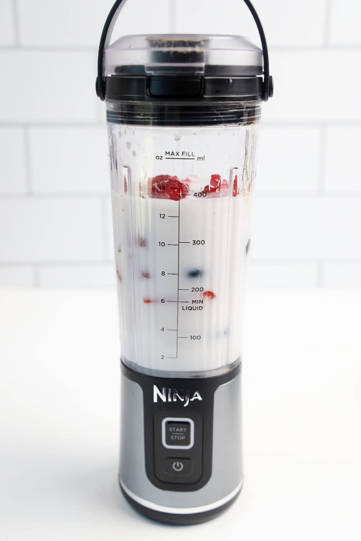 Unblended vegan triple berry smoothie ingredients in a Ninja blender cup.