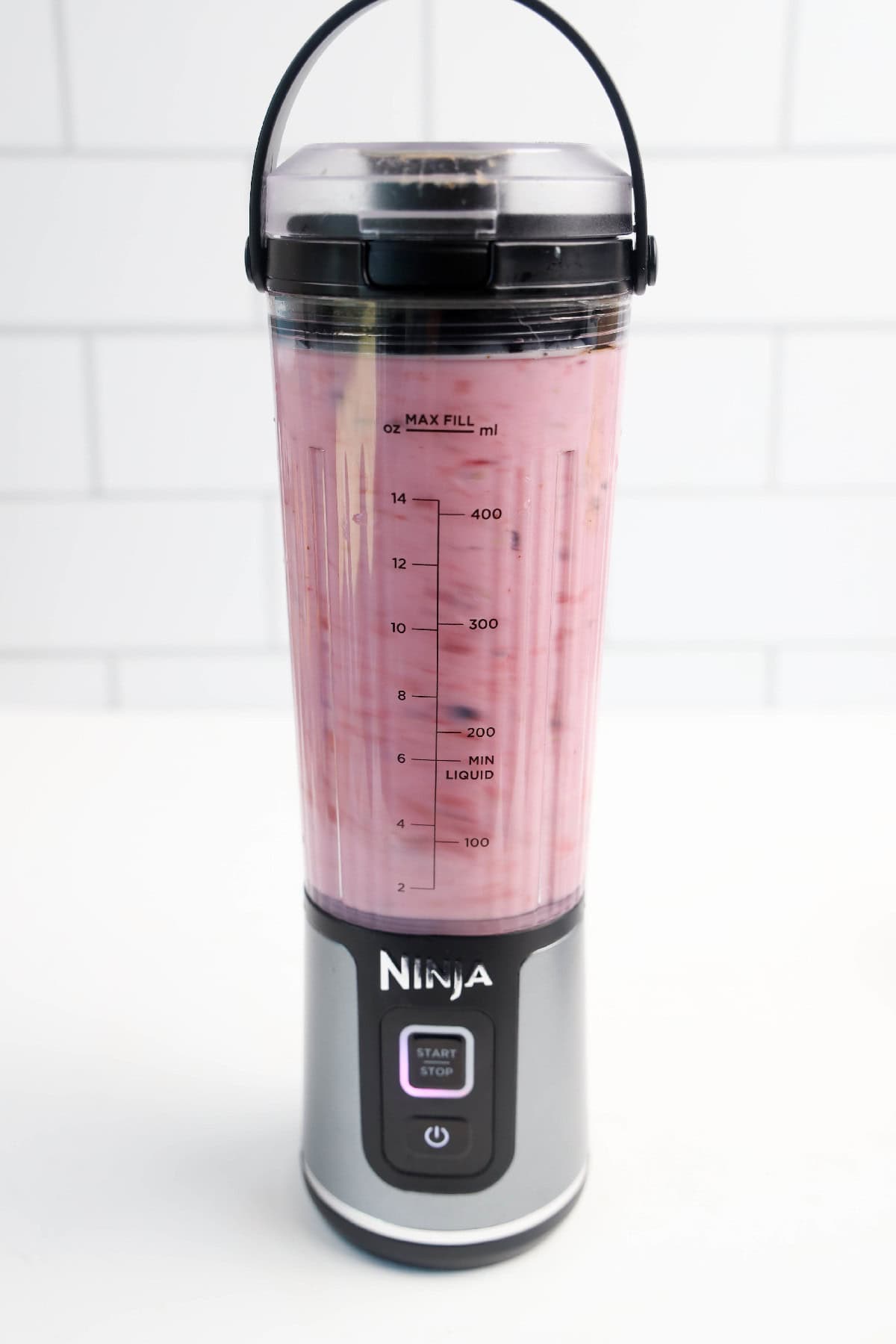 Mid-blend shot of a triple berry smoothie mixing in a Ninja personal blender.