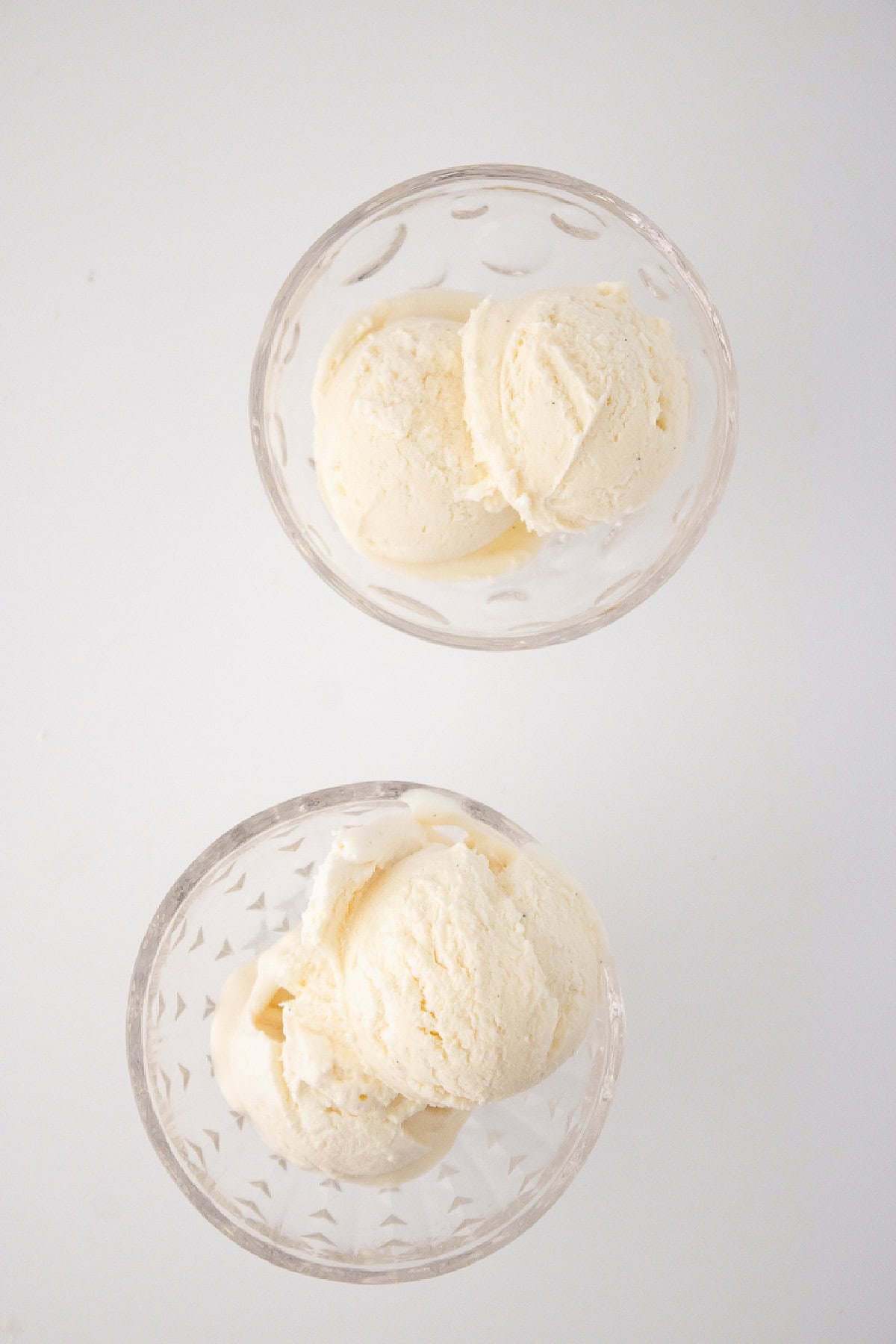 Two glass bowls filled with scoops of homemade vanilla bean ice cream.