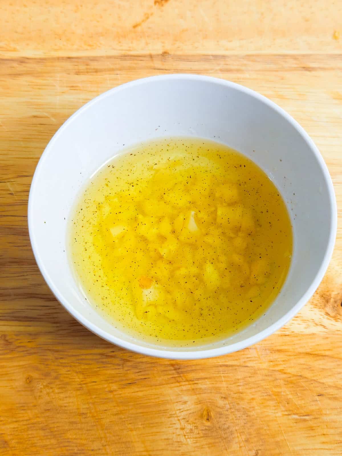 Bowl of olive oil mixed with garlic and black pepper for seasoning vegetables.