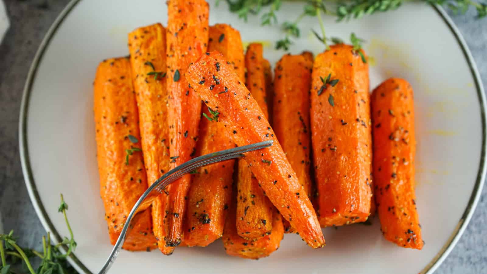 Close-up of fork picking up a tender, herb-seasoned air fryer carrots.