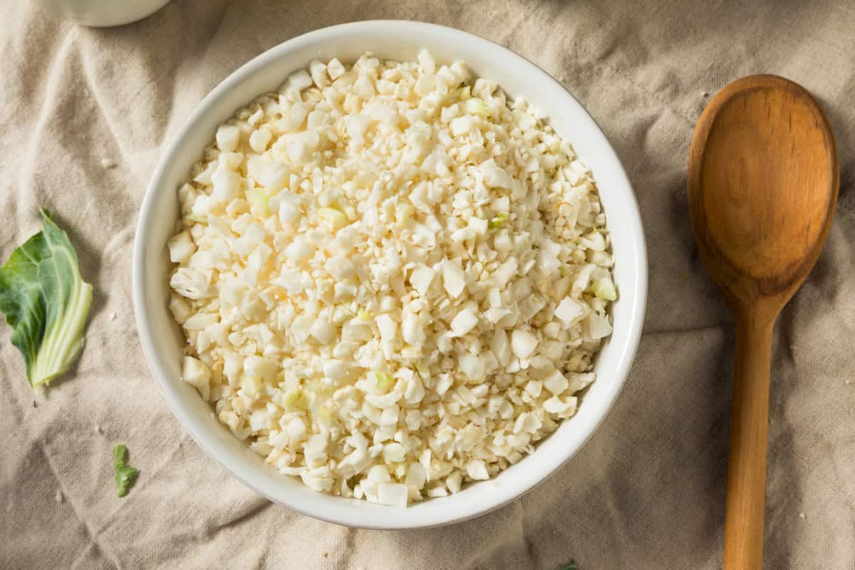 Freshly chopped cauliflower rice in a white bowl, perfect for low-carb and keto recipes.