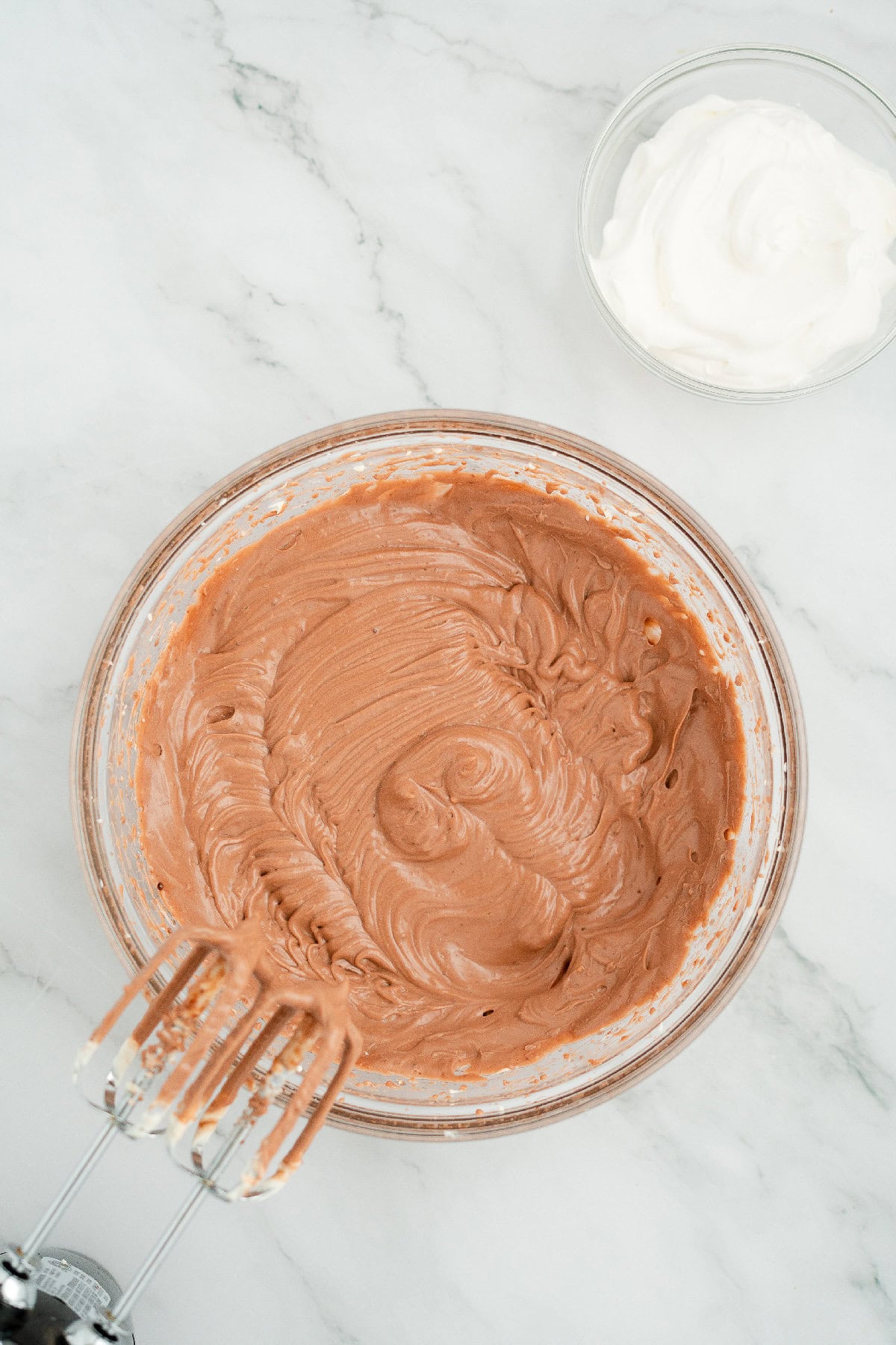 Creamy chocolate pudding and cream cheese filling blended in a bowl with whipped topping on the side.