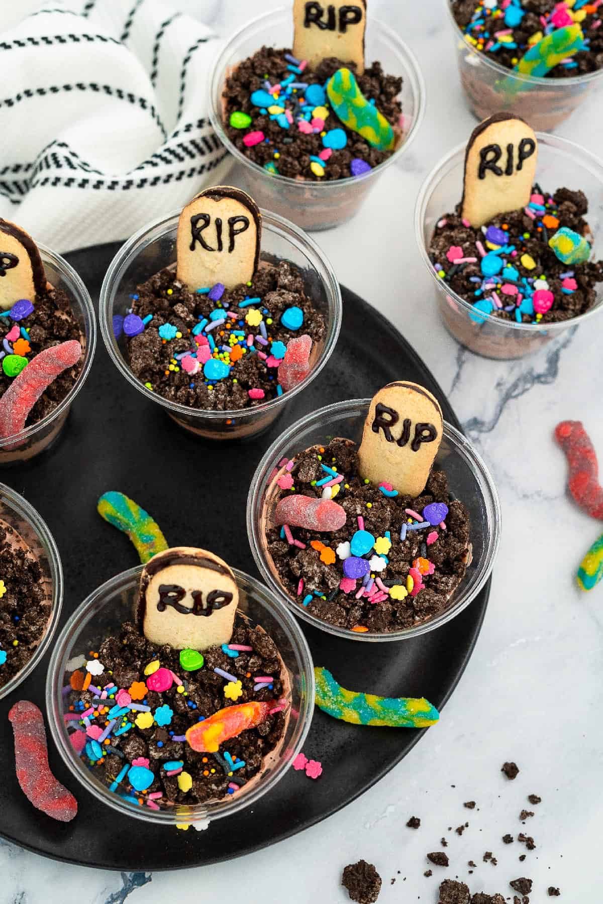 Chocolate dirt pudding cups decorated with Oreo “dirt,” gummy worms, and RIP Milano cookies for Halloween.