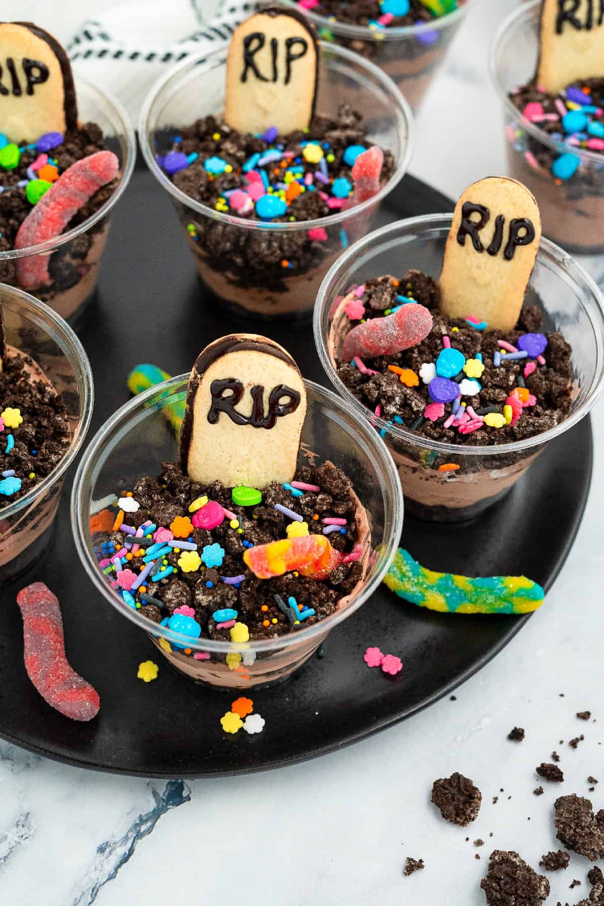 Fun Halloween dessert cups with layers of chocolate pudding, crushed Oreos, gummy worms, and cookie tombstones.