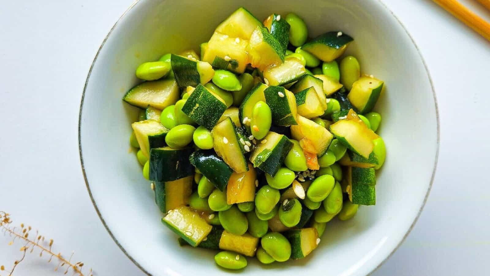 Close-up top view of cucumber and edamame salad in white bowl.