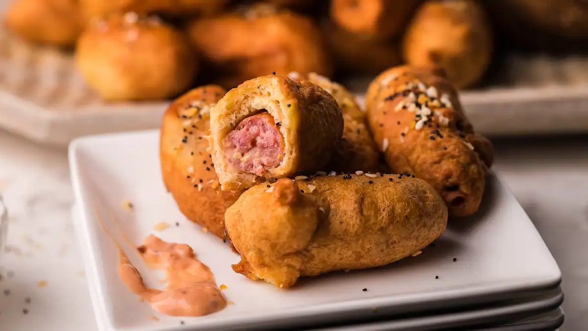 Mini hot dogs wrapped in bagel dough with dipping sauce.