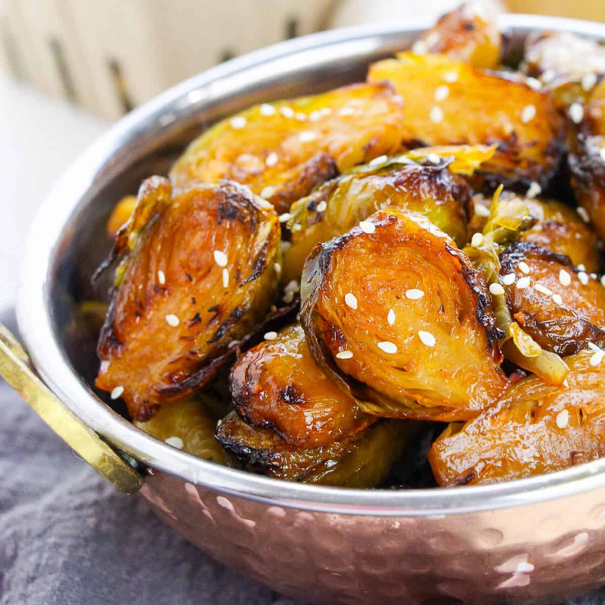 Close-up view of roasted Brussels sprouts with a spicy-sweet glaze and sesame seed topping.