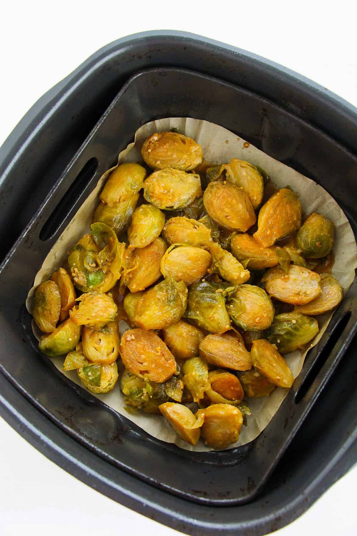 Air-fried Korean Brussels sprouts in parchment-lined air fryer basket.