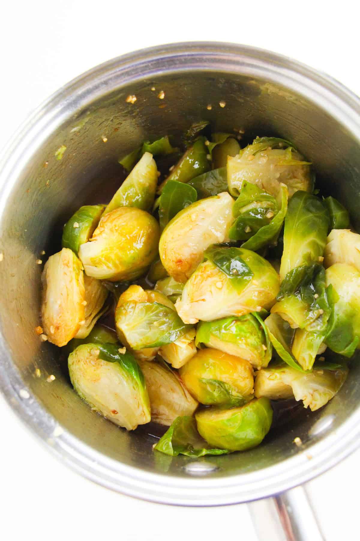 Brussels sprouts tossed in sweet and spicy Korean sauce inside a pot.