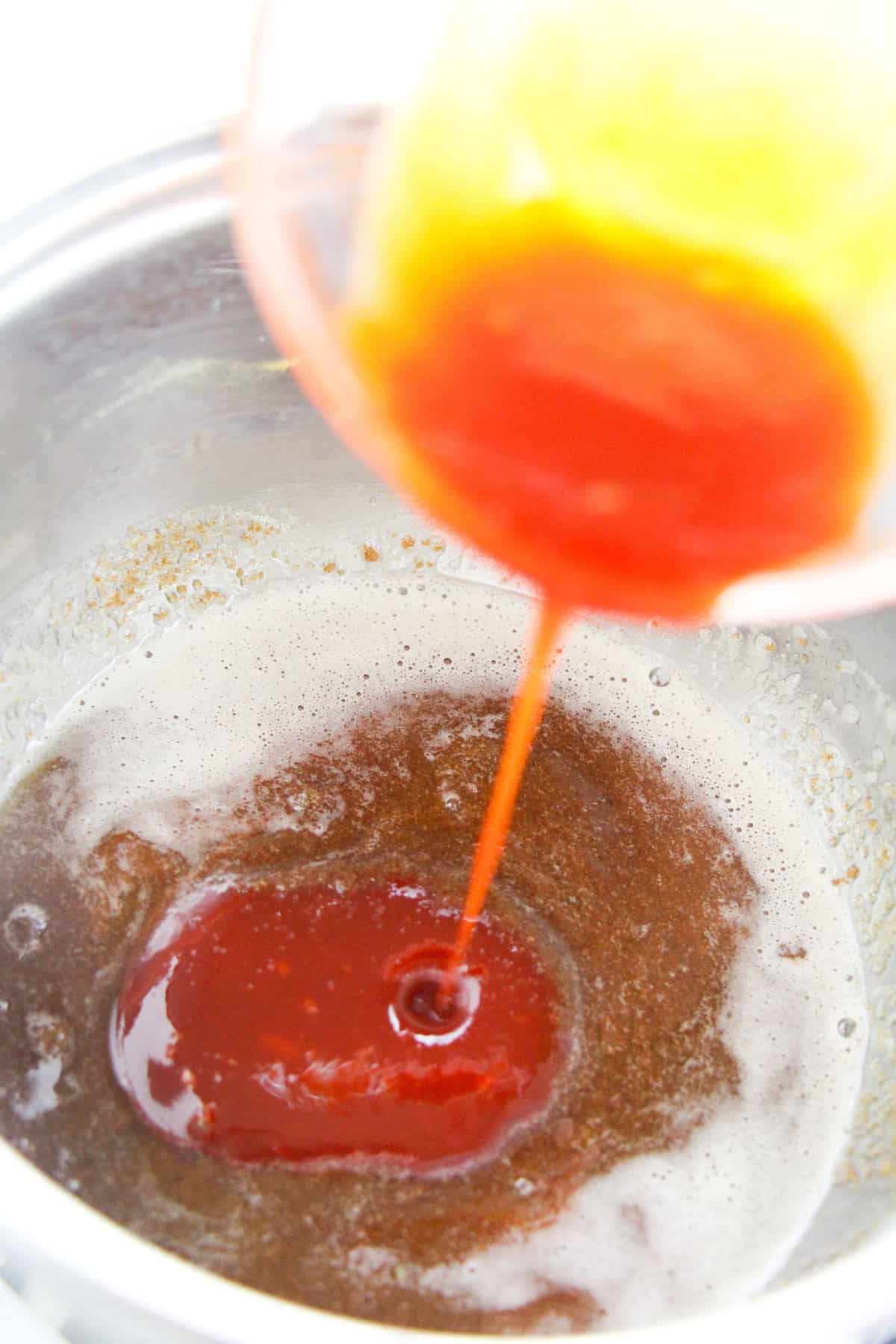 Pouring gochujang chili paste into sweet brown butter mixture for sauce.