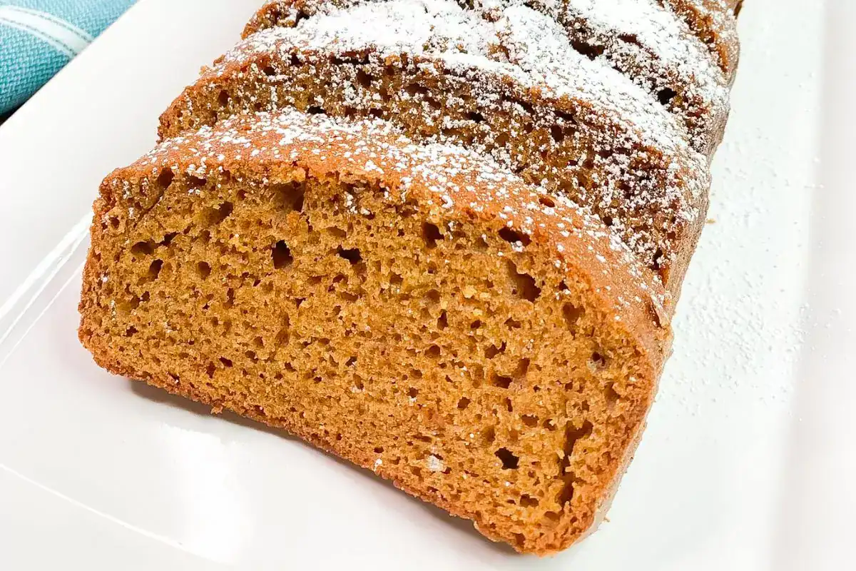 Pumpkin bread loaf sliced on cutting board.