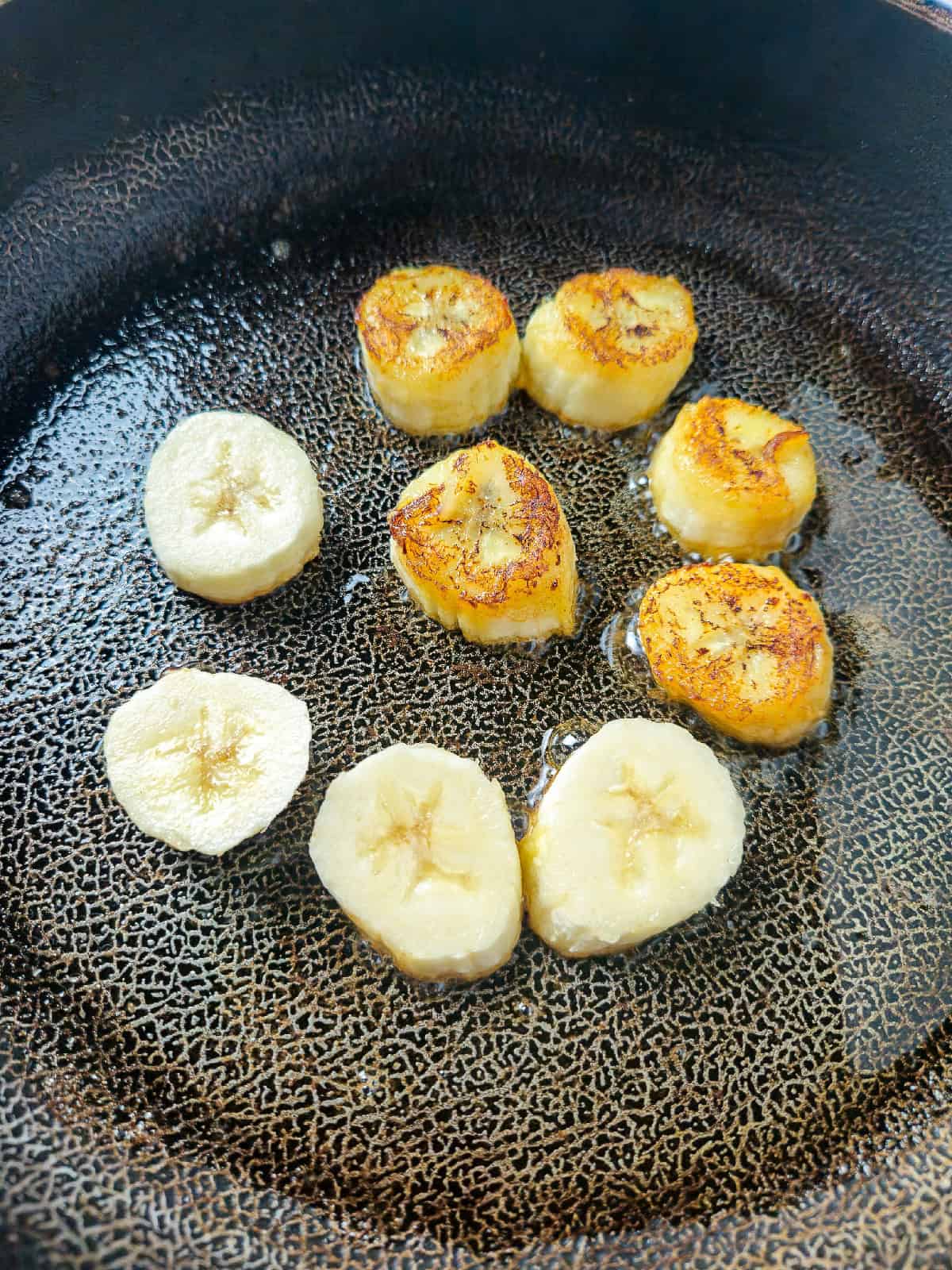 Bananas beginning to caramelize and turn golden while frying in butter.