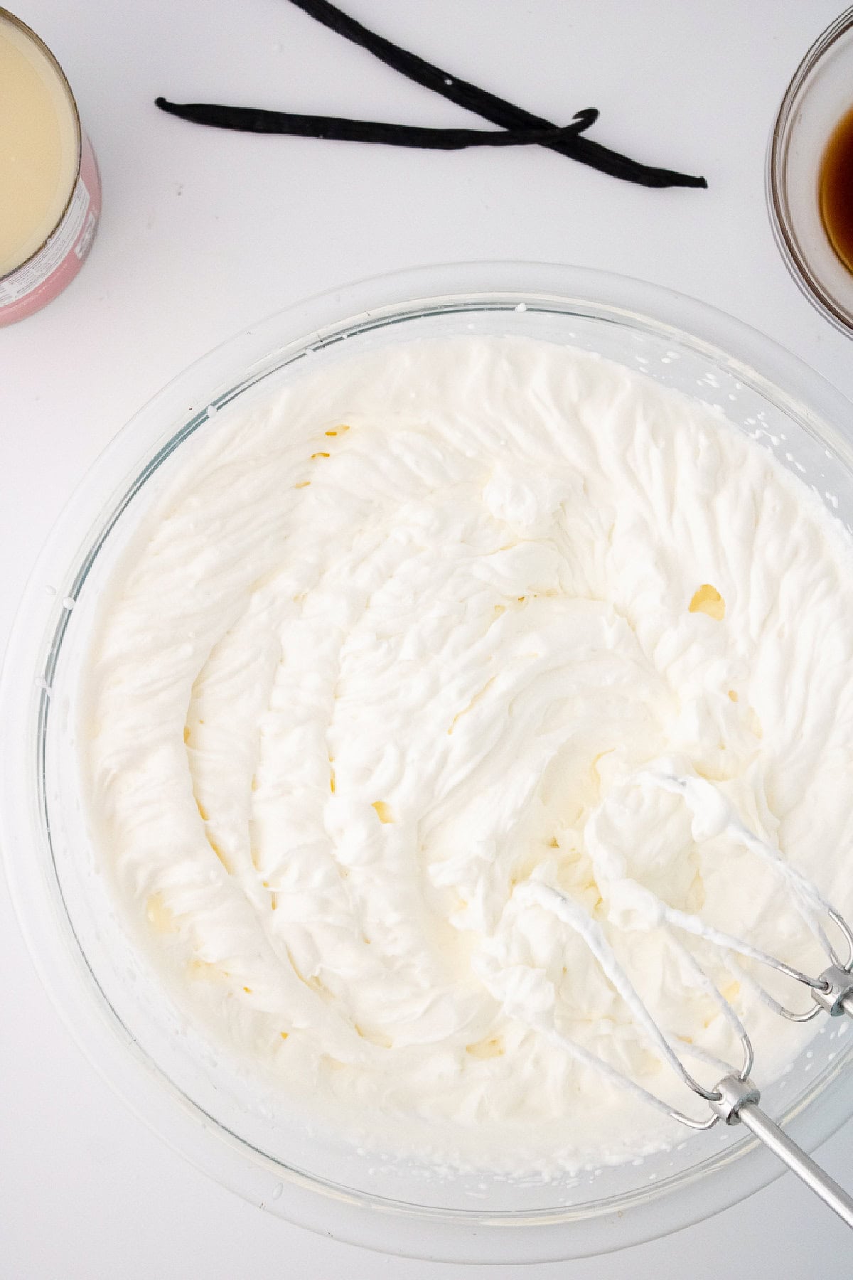 Fluffy whipped cream in a mixing bowl, the base for no churn vanilla bean ice cream.