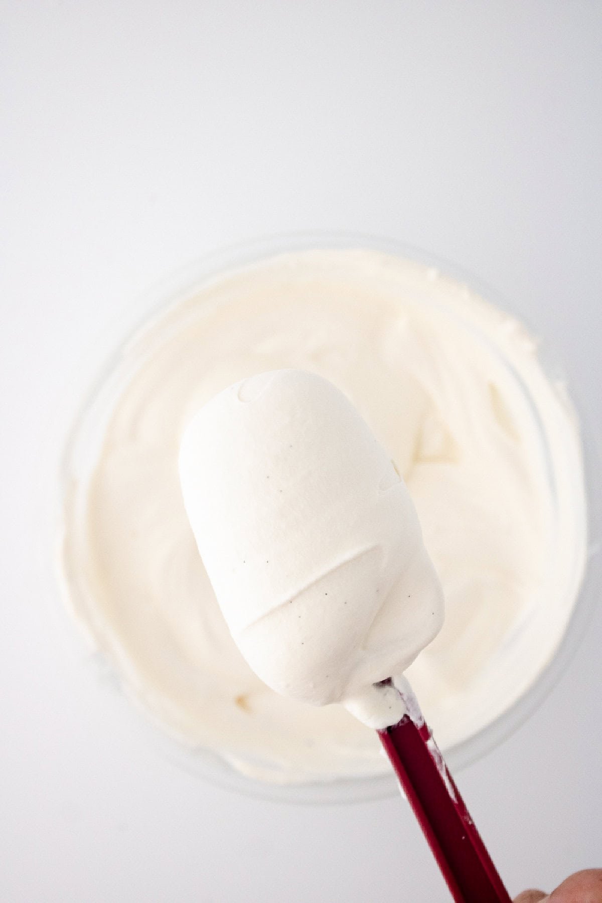 Close up of smooth vanilla ice cream mixture on a spatula with visible vanilla bean specks.