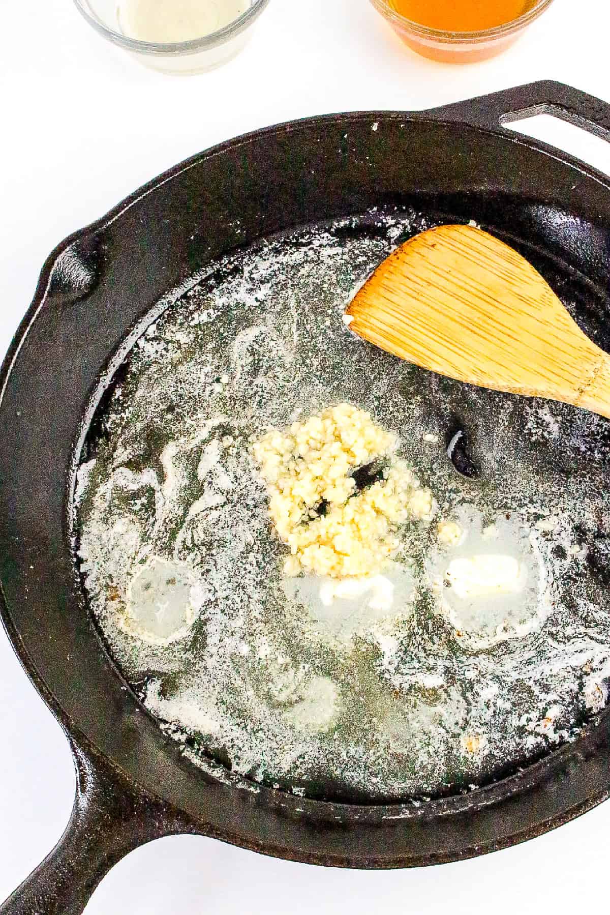 Fresh minced garlic sautéing in melted butter in a cast iron skillet.