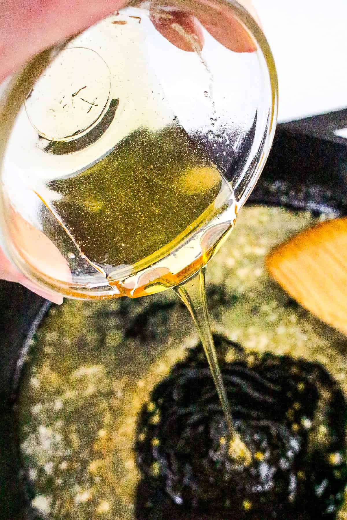 Golden honey being poured into a skillet with garlic and melted butter.