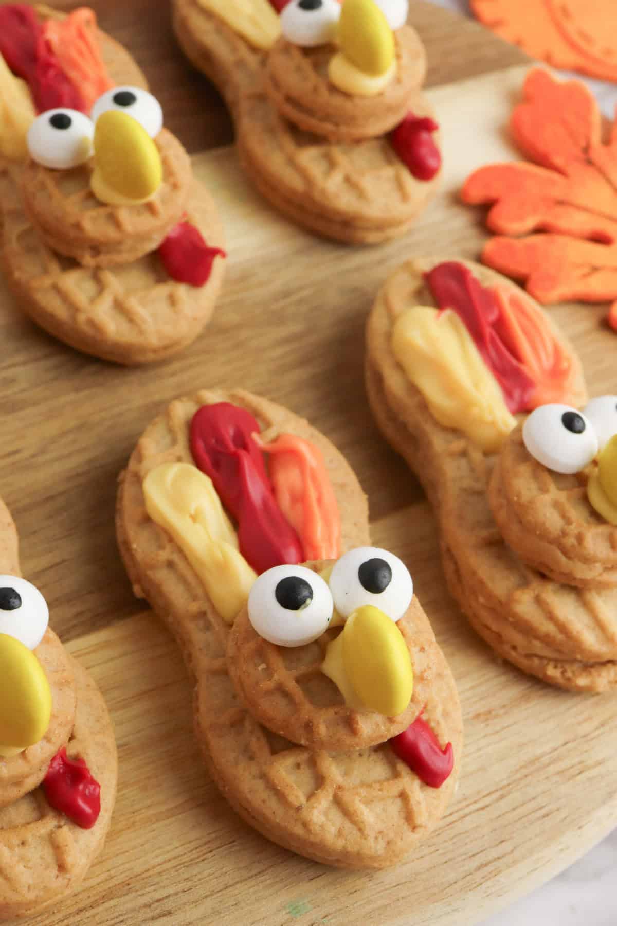 Thanksgiving turkey cookies made from Nutter Butters with red, orange, and yellow icing feathers and candy eyes.