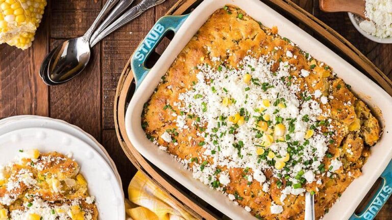 Golden air fryer corn casserole with a crispy top and soft, creamy center served in a white baking dish.