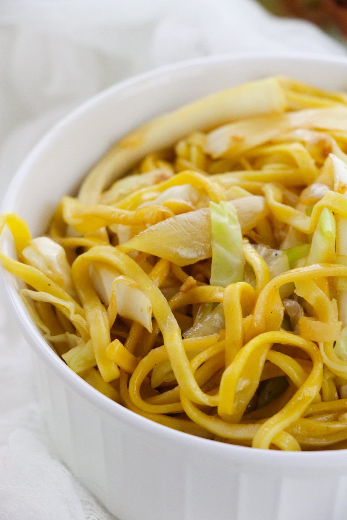 Close shot of chow mein noodles mixed with stir-fried cabbage and onions.