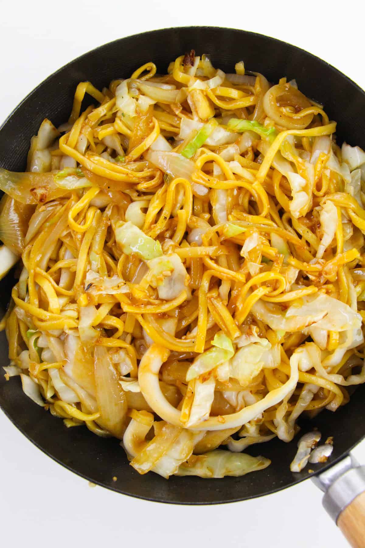 Chow mein noodles stir-fried with cabbage and onions in a wok.