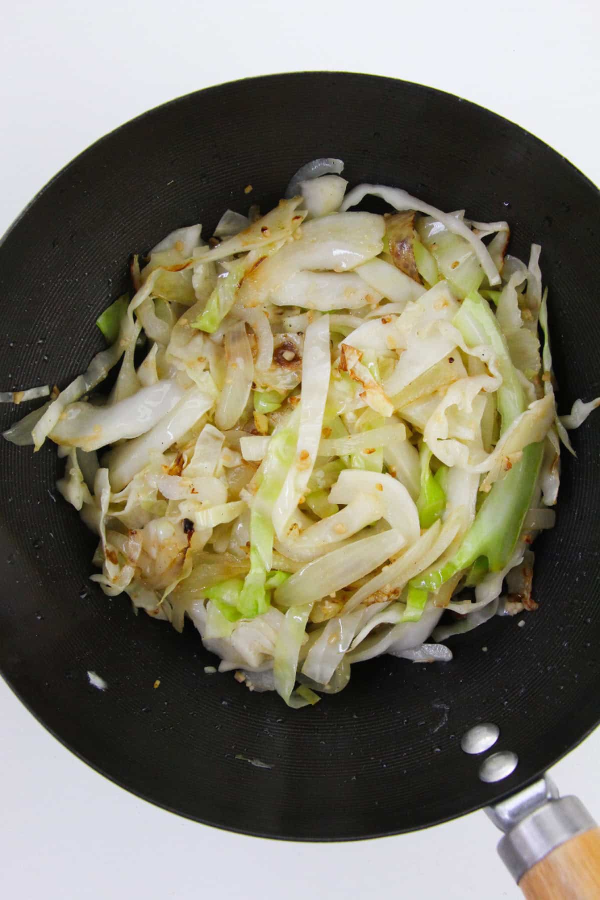 Cabbage and onions sautéed until slightly browned in a wok.