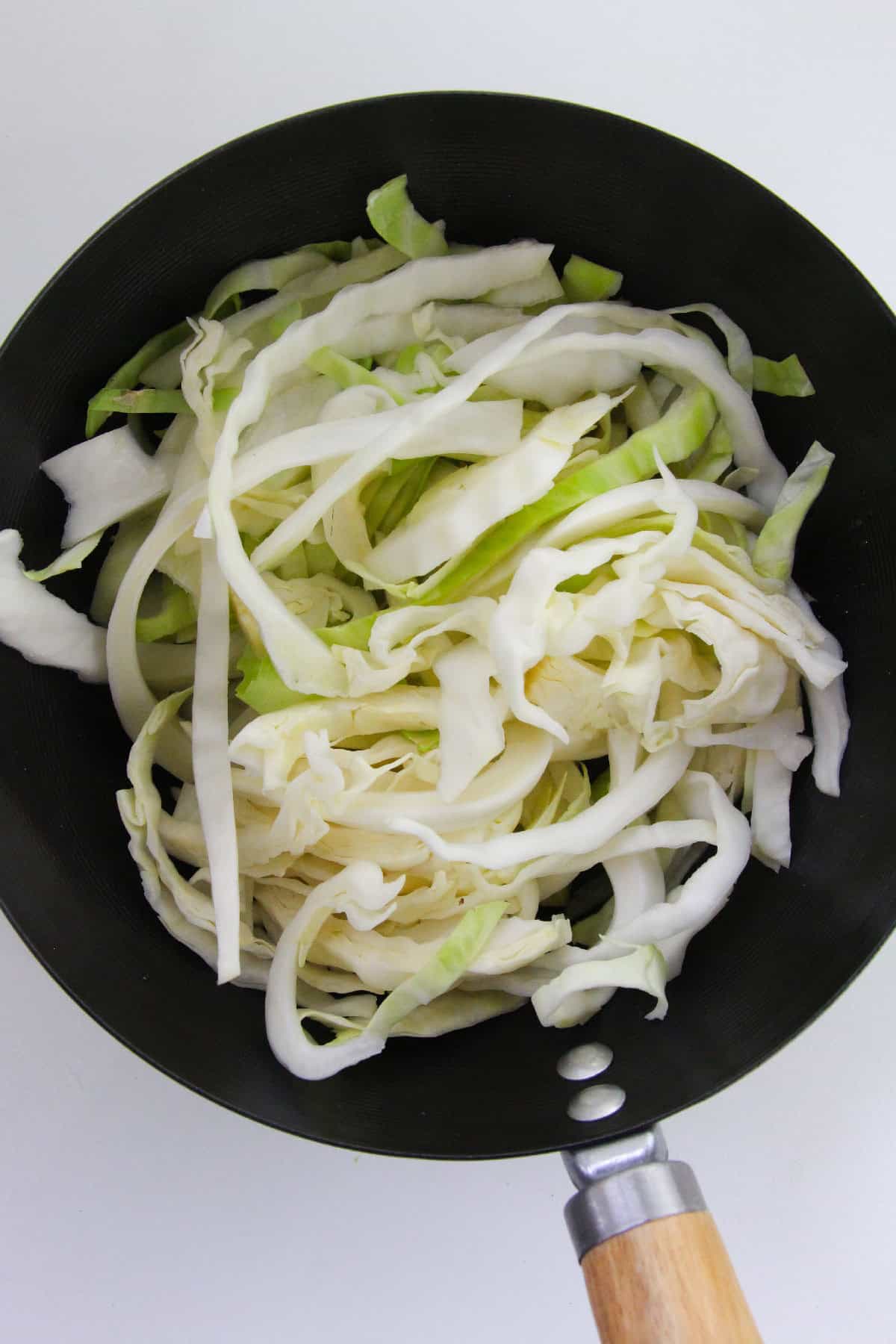 Shredded cabbage in a wok before cooking.