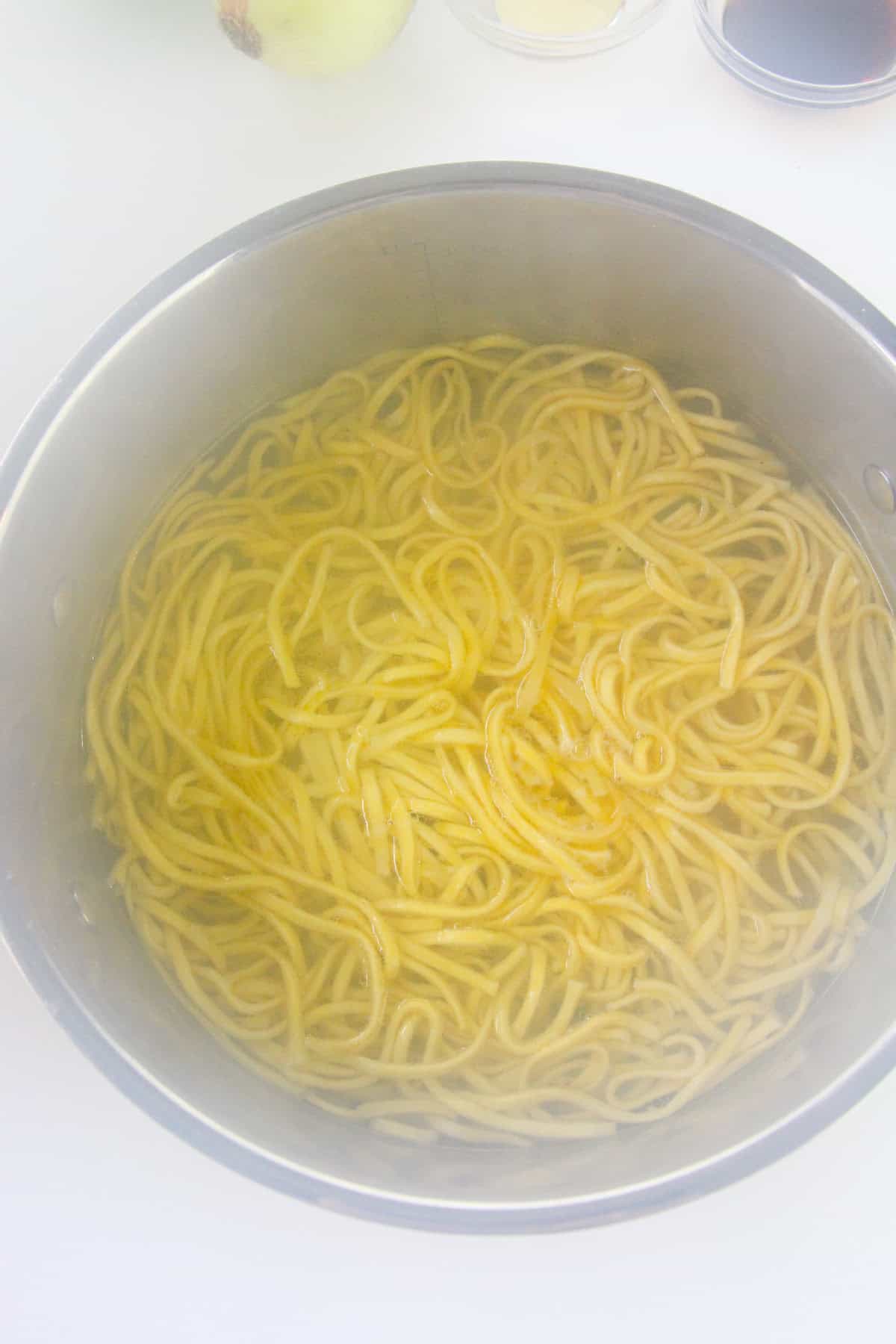 Freshly cooked noodles in a pot with steam rising.