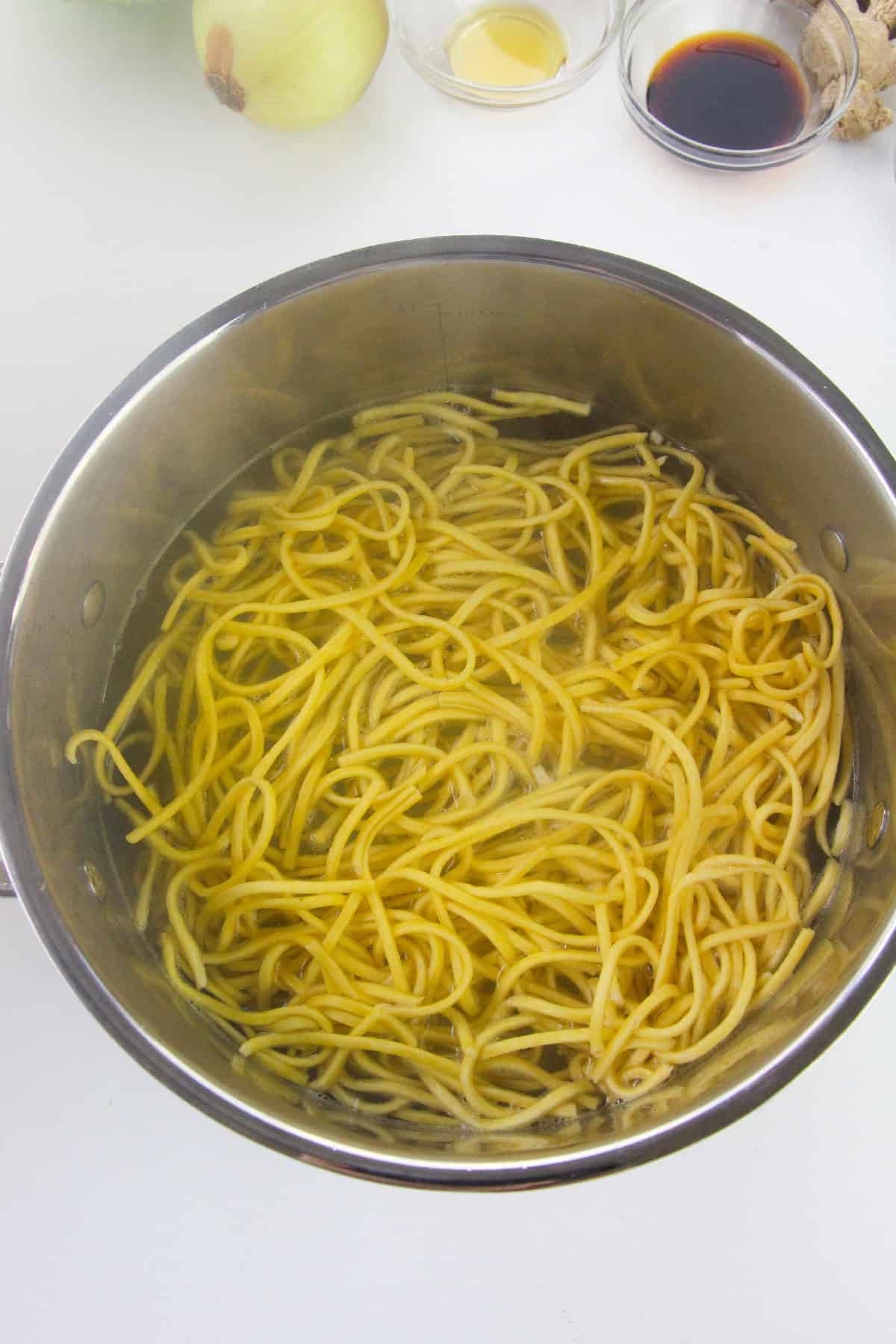 Uncooked noodles boiling in a pot of water.