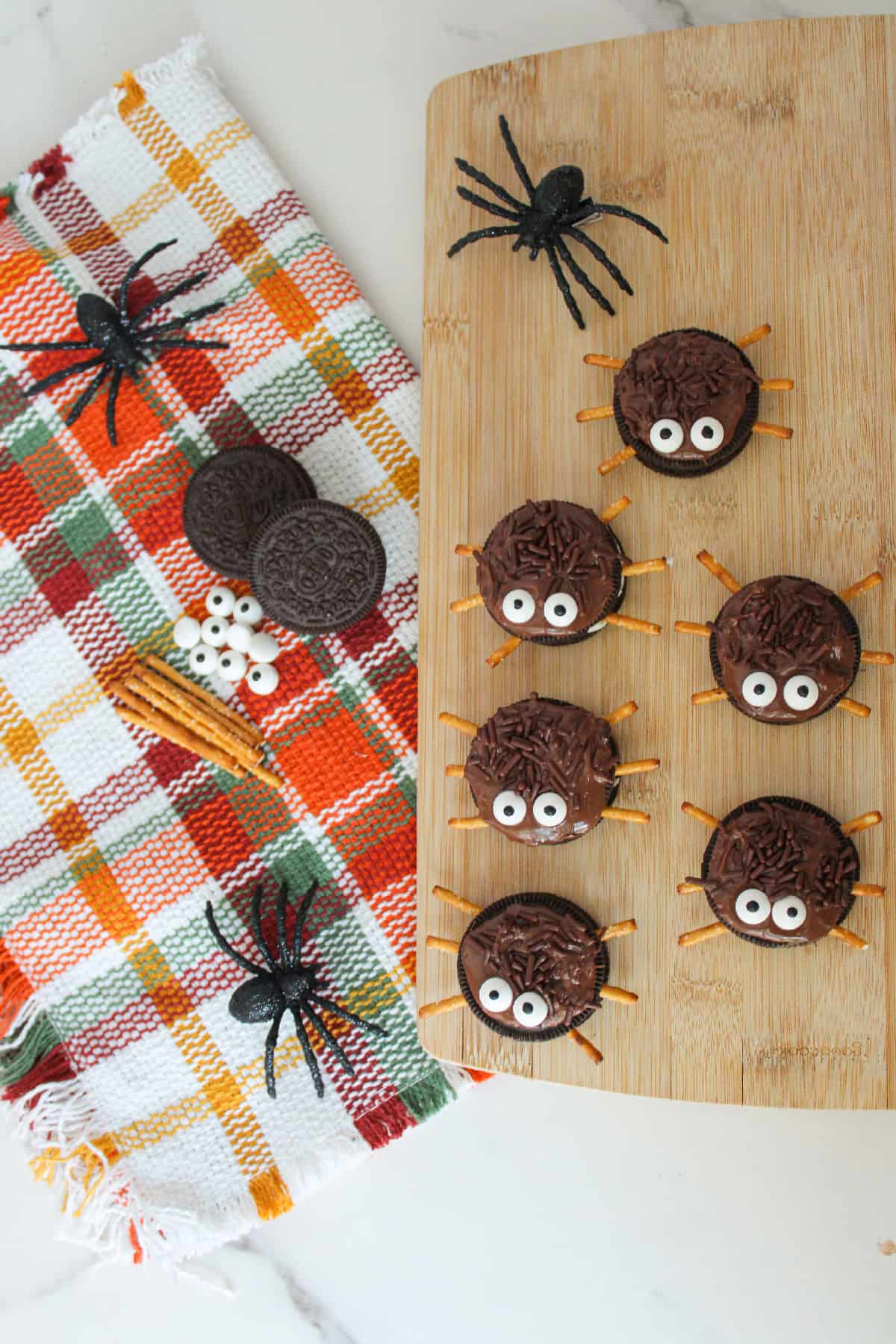 Close-up of Oreo spider cookies topped with chocolate sprinkles, candy eyes and pretzel legs for Halloween.