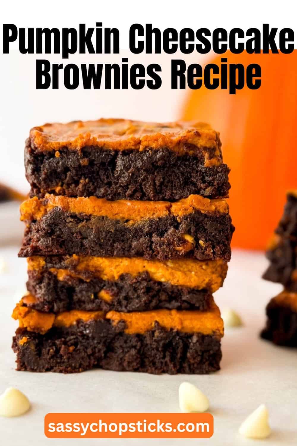 Stack of pumpkin cheesecake brownies close up showing moist chocolate brownie and bright pumpkin cheesecake layers.
