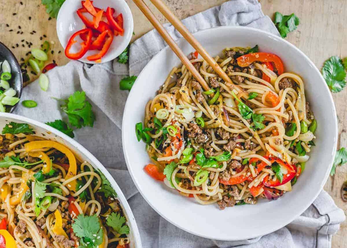 Spicy udon noodle stir fry with vegetables and sauce served in a bowl.