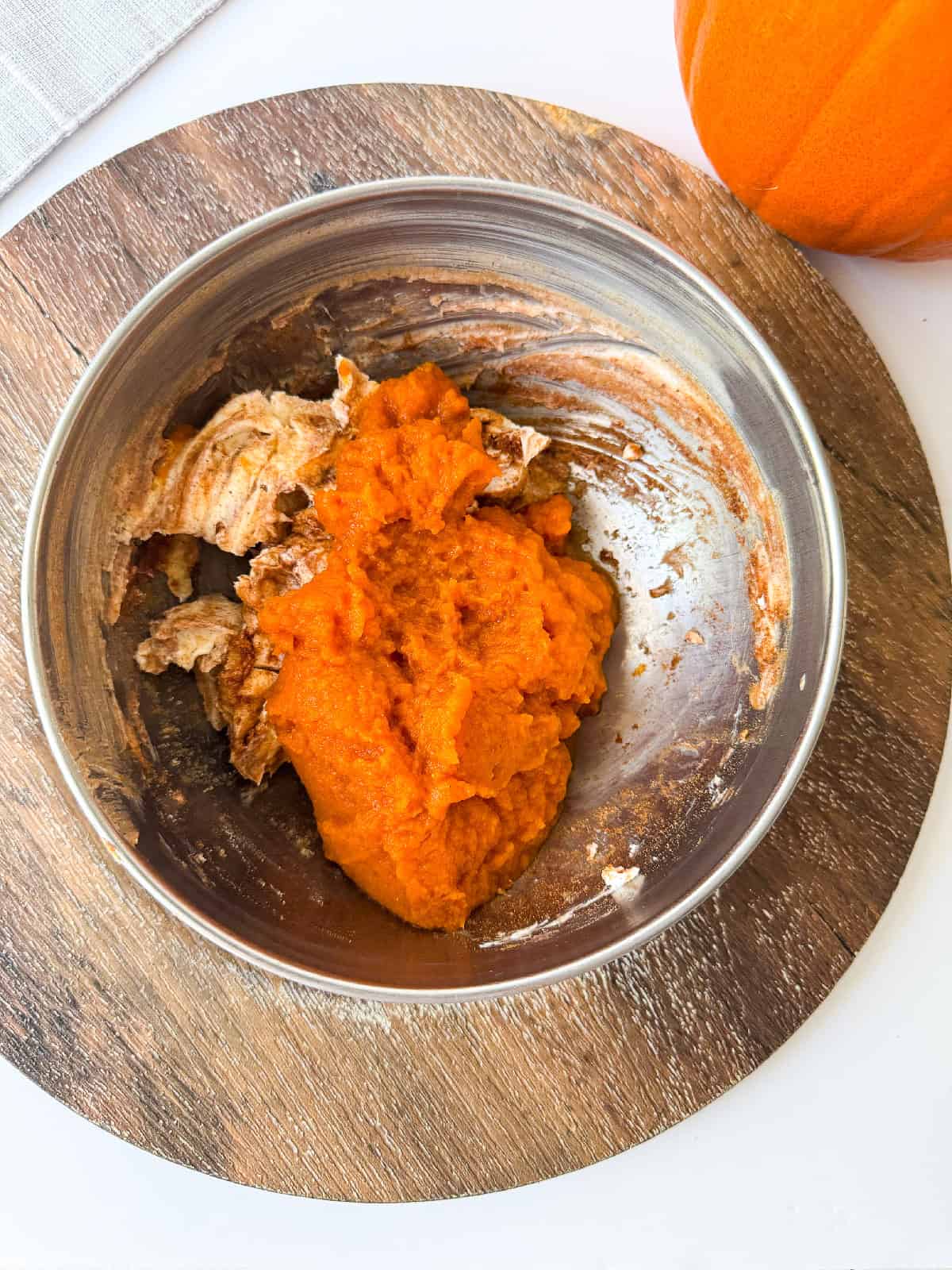 Bowl containing pumpkin puree and spices being mixed together for pumpkin layer.