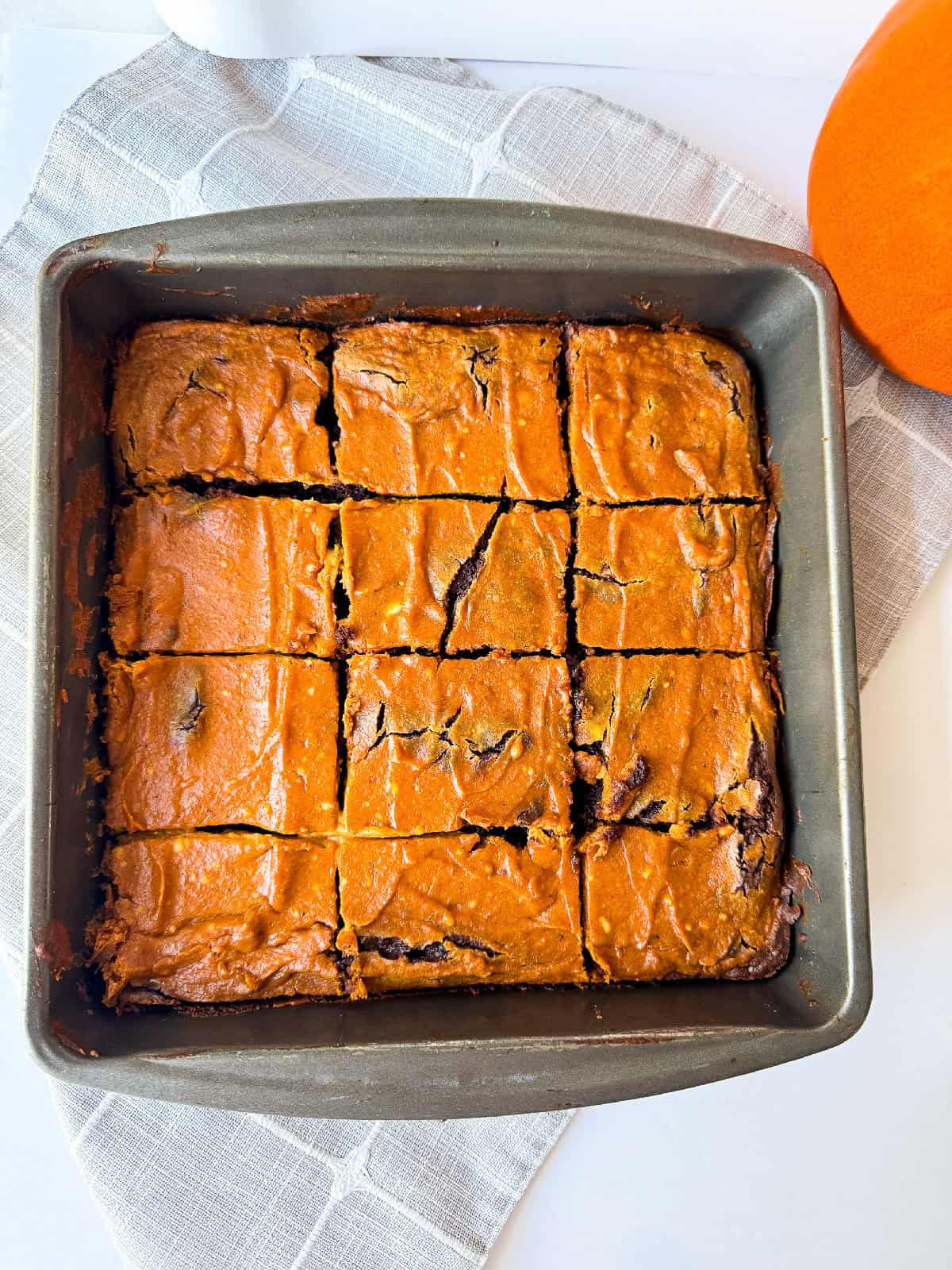 Baked pumpkin brownies cut into squares in the pan, ready to serve.
