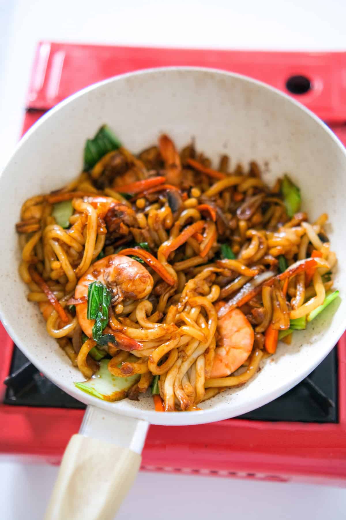 Yaki udon noodles stir-fried with shrimp and vegetables in a white skillet.