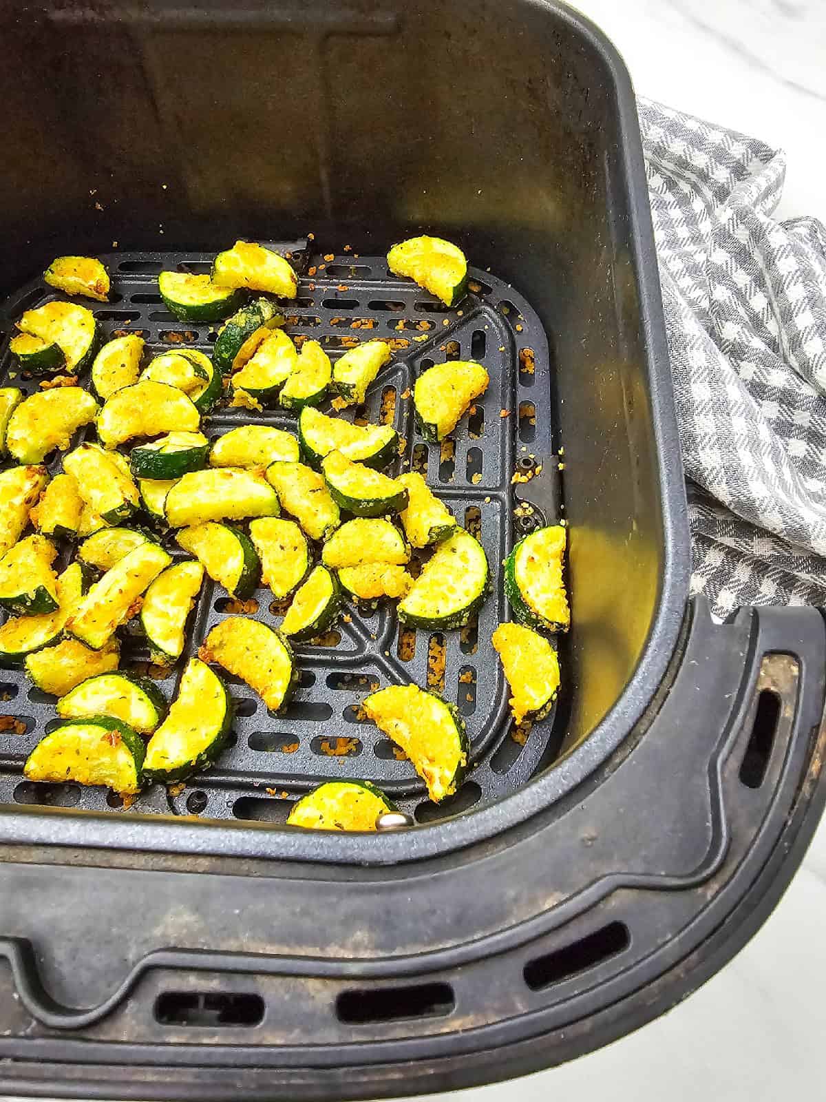 Close-up of crispy air fryer zucchini parmesan after cooking, showing lightly browned edges and an even coating.