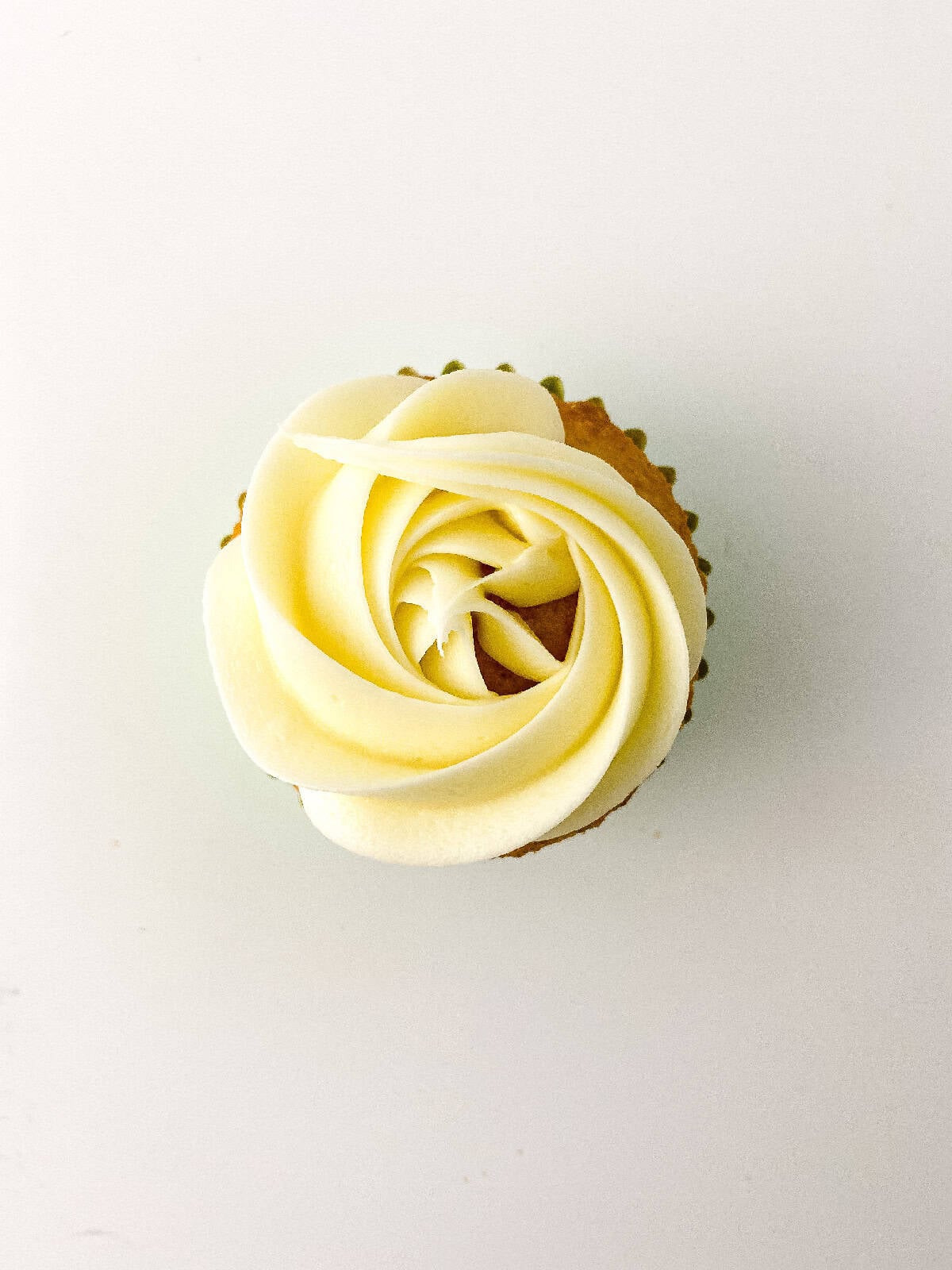 Vanilla cupcake topped with a smooth white buttercream rosette piped in a spiral pattern.