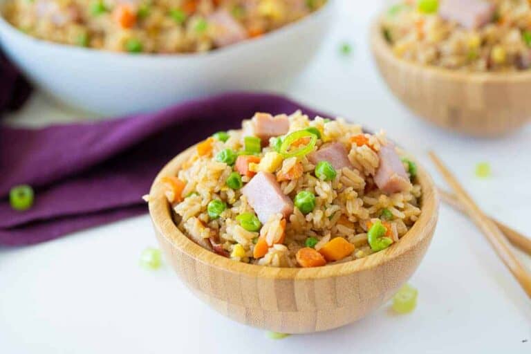 Ham fried rice served in a skillet with golden rice and colorful veggies.
