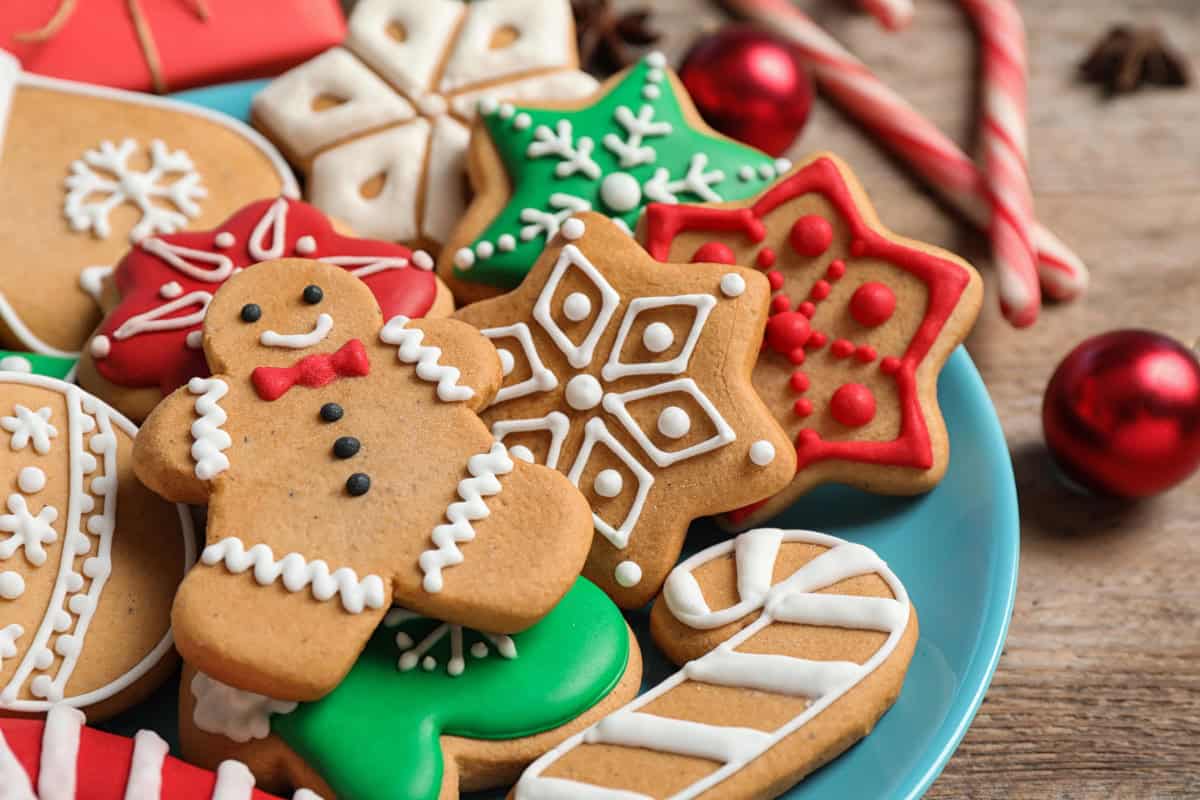 Assorted Christmas cookies including a smiling gingerbread man, snowflakes, and stars with red, white, and green icing on a blue plate.