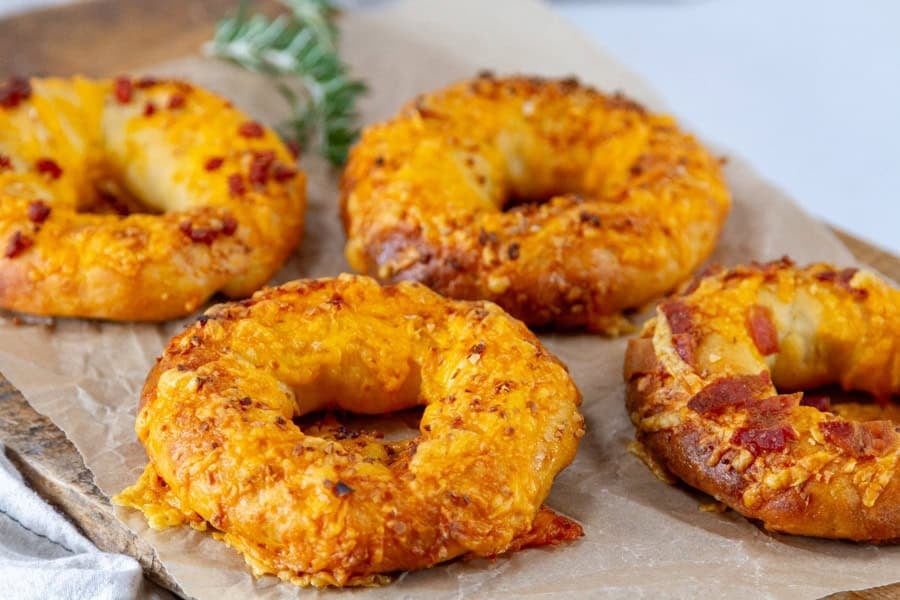 Loaded stuffed bagels filled with cream cheese, bacon, and green onions on a plate.