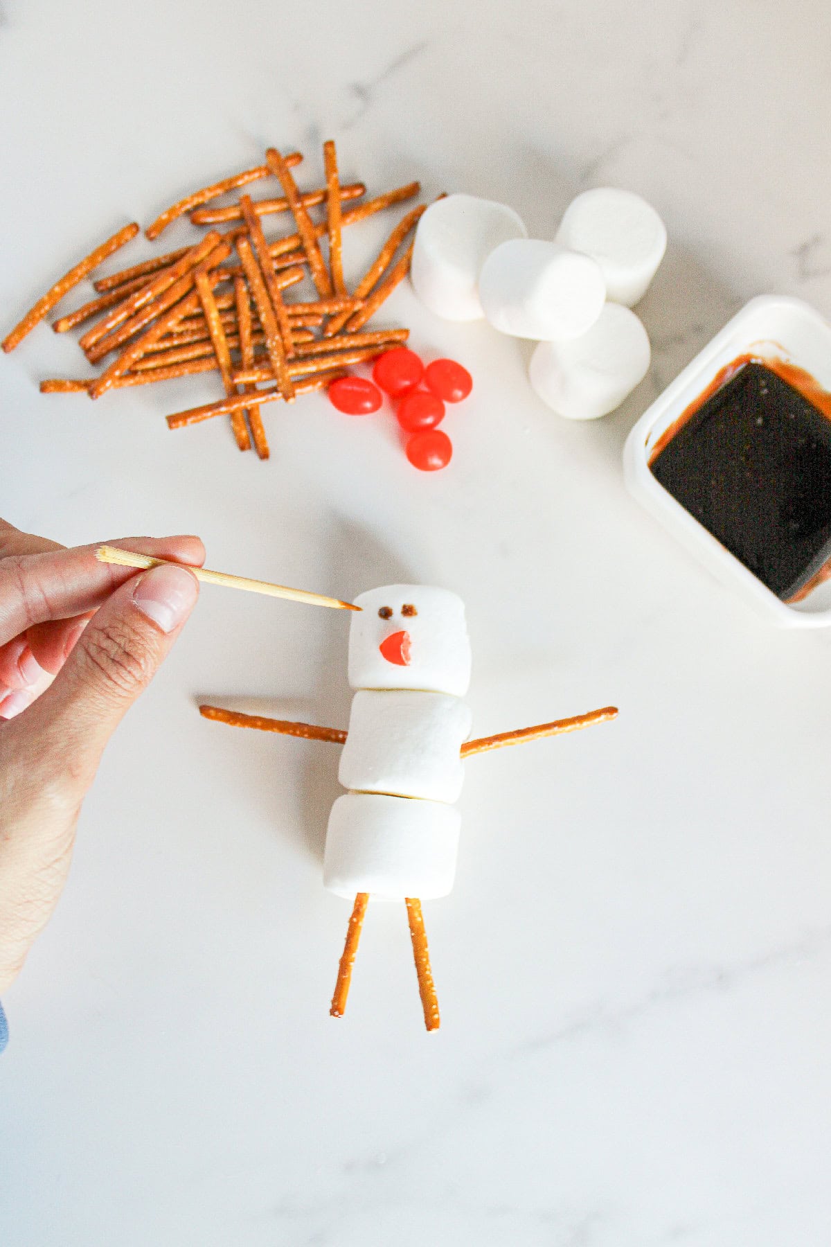 Using a toothpick dipped in chocolate syrup to draw the snowman's eyes.