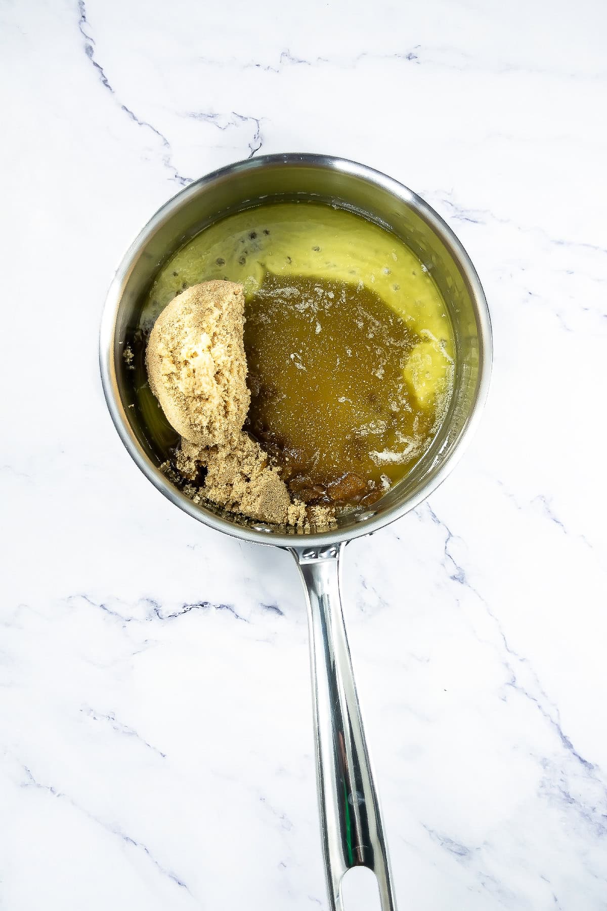 Brown sugar and honey added to melted butter in a saucepan to make brittle syrup.