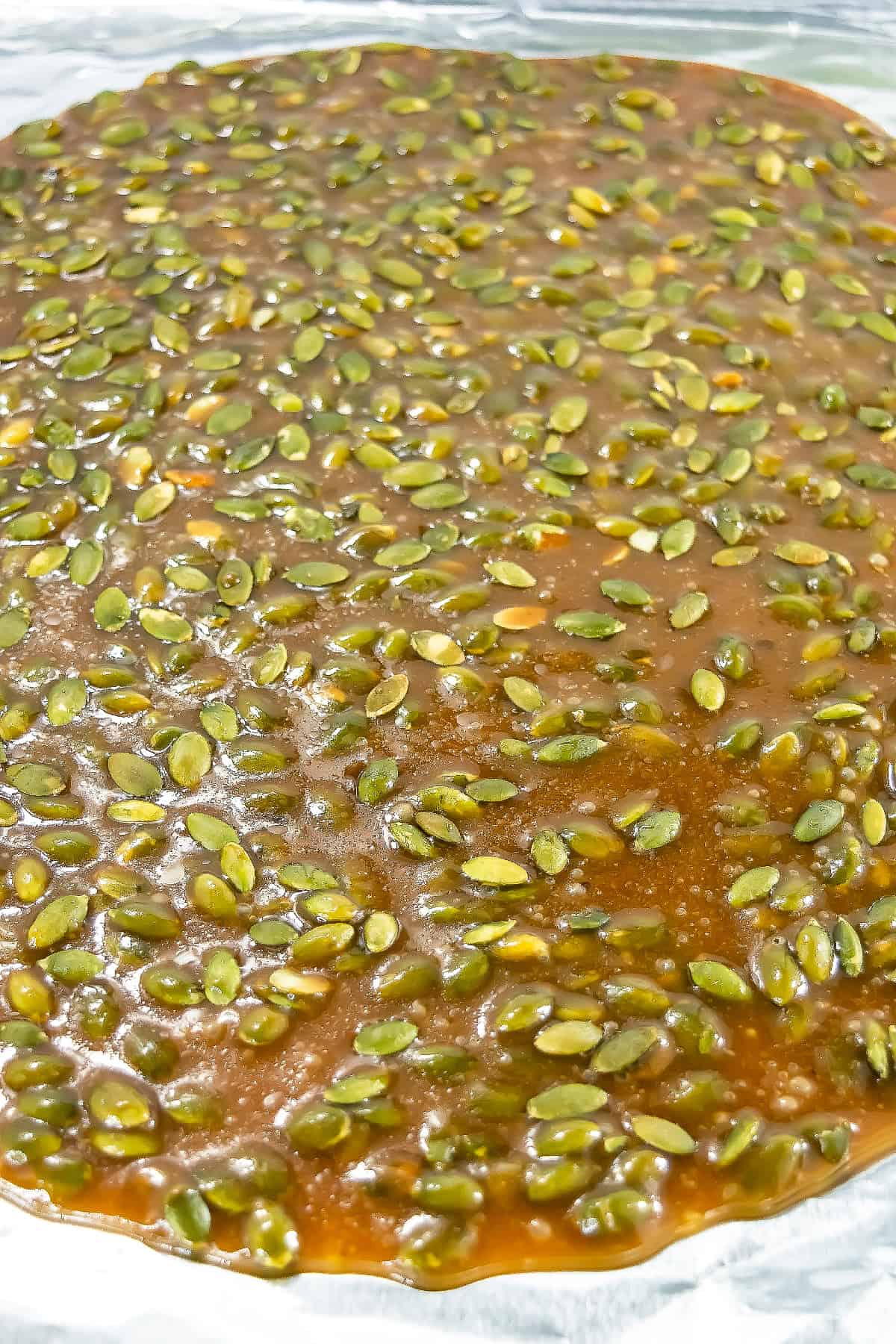 Close-up of glossy pumpkin seed brittle with a golden caramel coating.