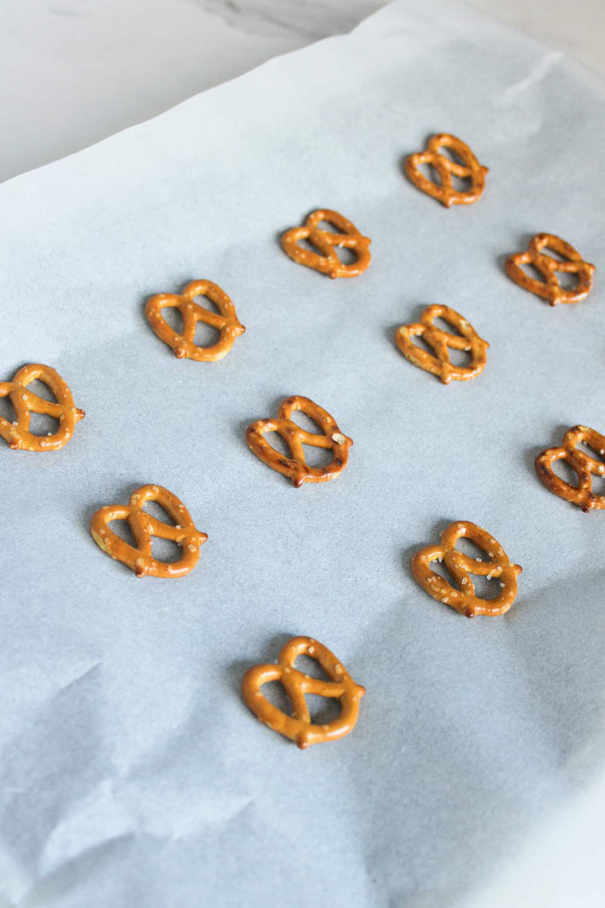 Mini pretzels arranged in neat rows on a baking sheet lined with parchment paper, ready for assembling reindeer treats.